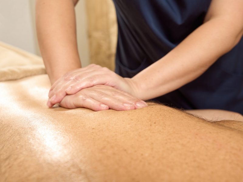 Woman osteopath works with a patient spine in wellness center